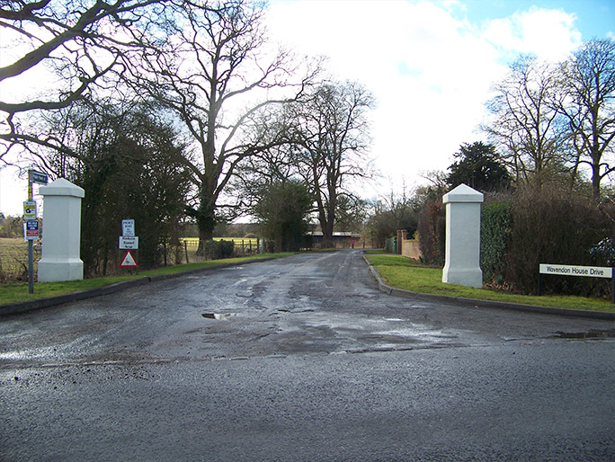 a driveway with two white pillars either side